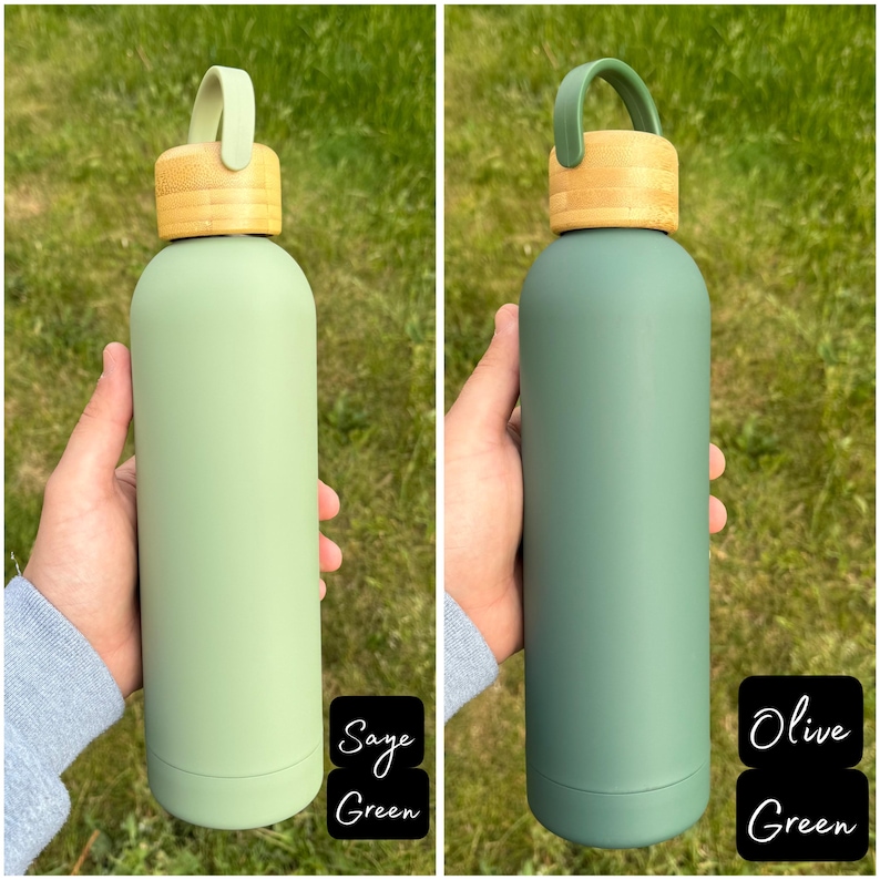 Two earth-toned water bottles held outdoors. The left one is a light, muted Sage Green with a bamboo lid and sage-coloured loop handle. The right one is a deeper Olive Green with a matching green handle and the same bamboo lid.