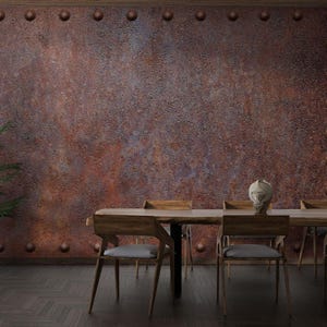 Könnte beinhalten: Ein rustikales Esszimmer mit einem Holztisch und Stühlen vor einer Wand aus rostigem Metall. Die Wand hat einen abgenutzten, industriellen Look mit Nieten und einer strukturierten Oberfläche.
