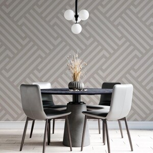 May include: A dining room with a round table and four chairs. The table is made of dark wood and has a concrete base. The chairs are upholstered in gray fabric. The walls are covered in a geometric wallpaper with a light gray and white pattern. A modern light fixture hangs from the ceiling.