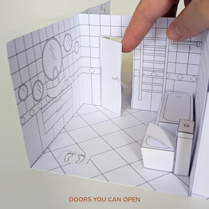 May include: A paper craft model of a bathroom interior with black and white line art. The scene features a tiled floor, a sink, a bathtub, a toilet, and a door that can be opened. The text DOORS YOU CAN OPEN is printed at the bottom.