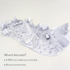 May include: A detailed, white papercraft village scene with a central Christmas tree, houses, and figures. The image includes text: "WHATS INCLUDED?" and "2 PDF FILES IN A4 AND LETTER SIZE" and "DETAILED INSTRUCTIONS".