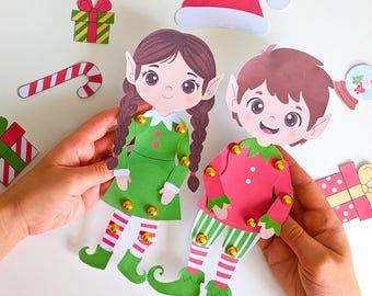 May include: Two paper elf cutouts, one in green and one in red, with gold bells and green elf shoes. Additional Christmas-themed paper cutouts include a Santa hat, gifts, and a candy cane.