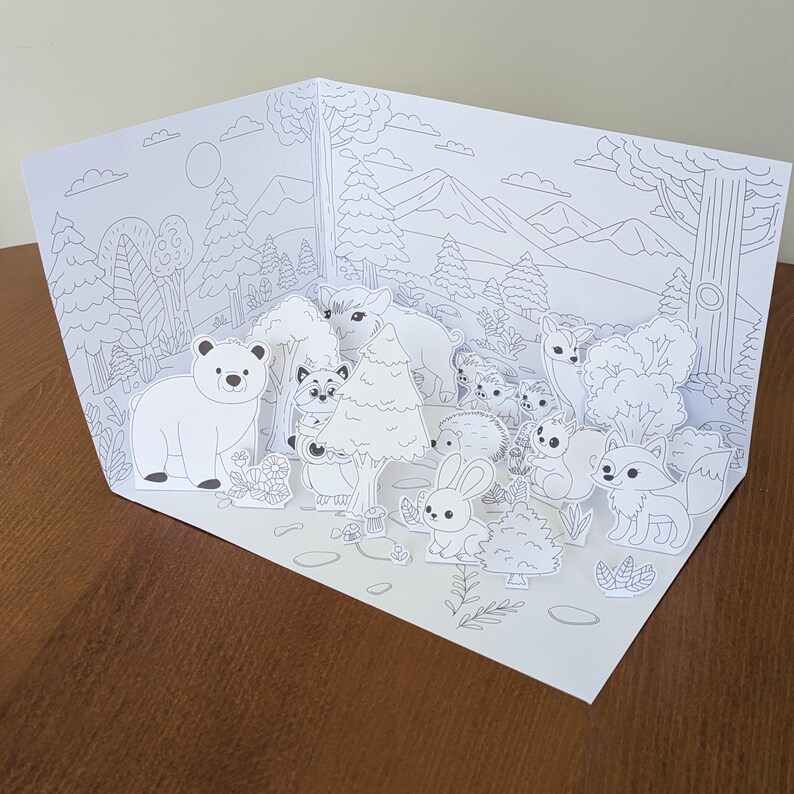 May include: A white, pop-up forest scene with various woodland animals, including a bear, raccoon, rabbit, and fox. The paper art features a detailed, black and white illustration of trees, mountains, and foliage, creating a 3D effect.
