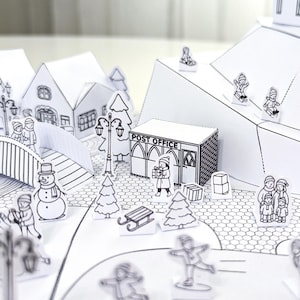 May include: A black and white papercraft winter village scene with a post office, houses, trees, and figures ice skating and walking. The post office has the words "POST OFFICE" printed on it.