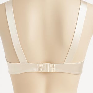 Puede incluir: Un sujetador color crema con tirantes ajustables y cierre de corchete. El sujetador est&aacute; hecho de un material liso, similar al sat&eacute;n. Las correas son anchas y se sujetan a la espalda del sujetador.