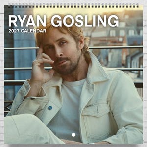 May include: A 2027 wall calendar featuring a portrait of Ryan Gosling. The calendar is bound with a black spiral wire at the top. The text RYAN GOSLING 2027 CALENDAR is printed in white at the top of the page over a photograph of the actor.
