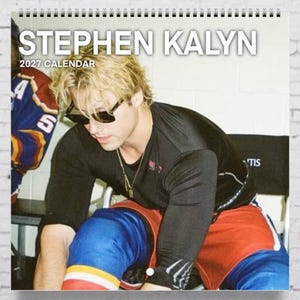 May include: A 2027 wall calendar featuring a photograph of a person with blonde hair wearing black sunglasses, a black long-sleeved shirt, and red and blue athletic shorts. The text STEPHEN KALYN 2027 CALENDAR is printed at the top of the page.
