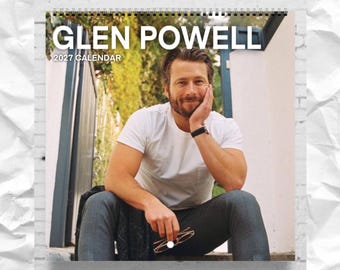 May include: A 2027 wall calendar featuring a photograph of Glen Powell. The cover displays the text GLEN POWELL 2027 CALENDAR in white capital letters. The image shows a person wearing a white t-shirt and dark trousers, sitting outdoors.