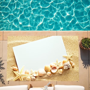 Könnte beinhalten: Ein weißes rechteckiges Schild mit einer Strandszene mit Muscheln und Seesternen auf einem braunen Hintergrund. Das Schild liegt auf einem braunen Teppich neben einem Schwimmbad.