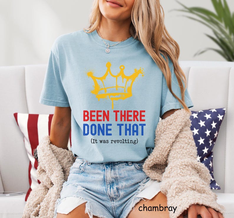 May include: Light blue t-shirt with a yellow crown graphic and the text "BEEN THERE DONE THAT (It was revolting)". The shirt is made of a soft material and is a casual style.