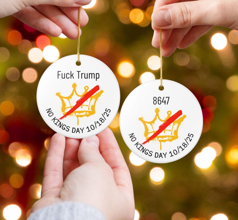 Puede incluir: Dos adornos navide&ntilde;os redondos de cer&aacute;mica blanca con hilo dorado. Uno tiene el texto "Fuck Trump" sobre una corona dorada con una raya roja y el texto "NO KINGS DAY 10/18/25". El otro tiene el n&uacute;mero "8647" y una corona similar.