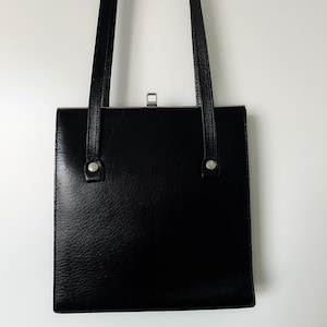 May include: A black leather shoulder bag with a flap closure and silver hardware.