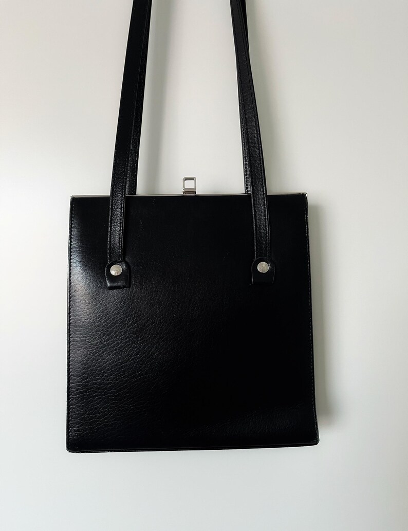 May include: A black leather shoulder bag with a flap closure and silver hardware.