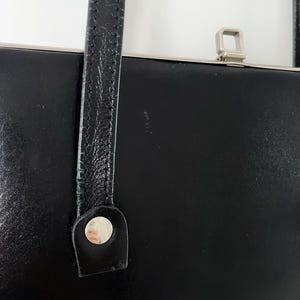 May include: Black leather handbag with a silver clasp and a single strap.