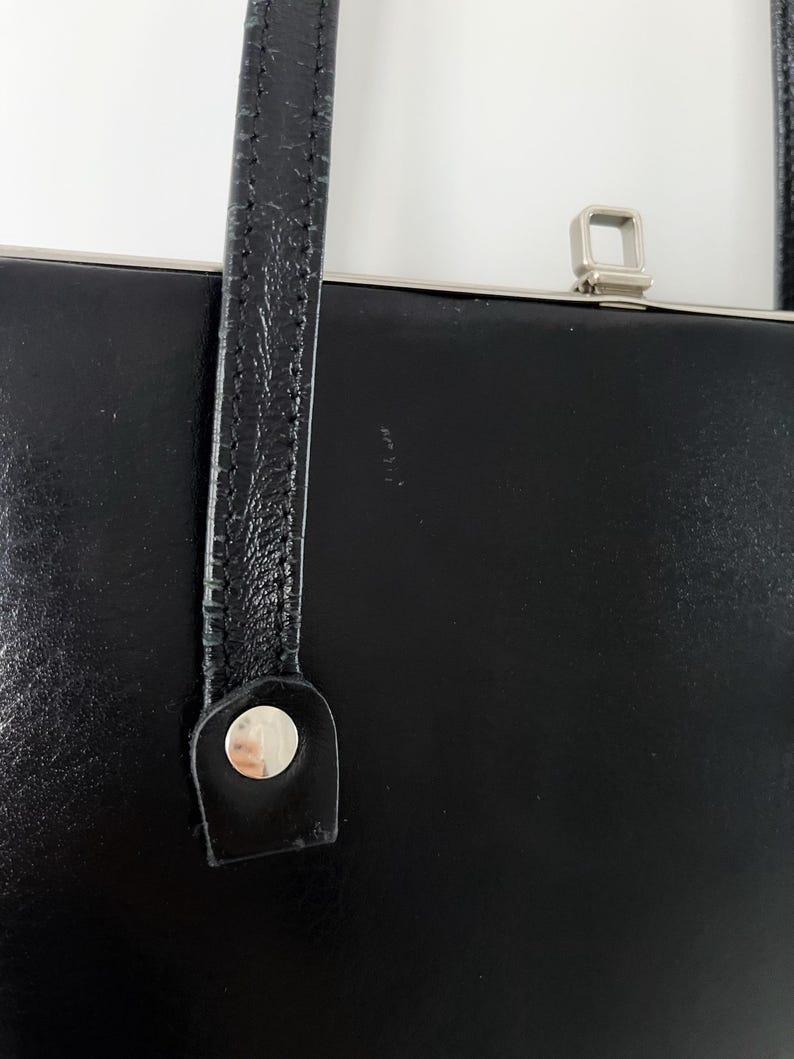 May include: Black leather handbag with a silver clasp and a single strap.