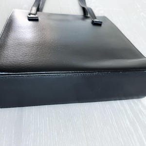 May include: A black leather tote bag with a simple design and two handles.