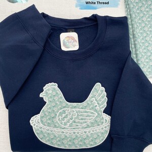 Embroidered Hen on Nest using fabric option I (i as in igloo) on a Navy sweatshirt.