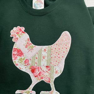 Embroidered chicken on a green sweatshirt. Fabric is a printed patchwork design with shades of pink florals and sage. The appliquéd fabric has a white zigzag border and stippling.