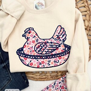 Hen on Nest using a Cream sweatshirt, Fabric M, and Navy blue thread.