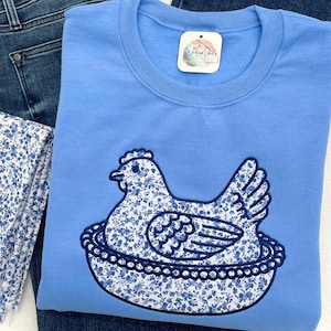 Embroidered Hen on Nest sweatshirt using Fabric B, Carolina Blue sweatshirt, and navy thread.