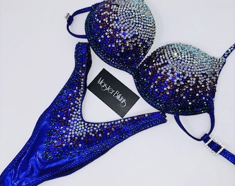 May include: A two-piece blue bikini set with sparkling embellishments. The top and bottom are adorned with iridescent rhinestones and a gradient effect. The set includes a tag that reads "Master Bikinis".