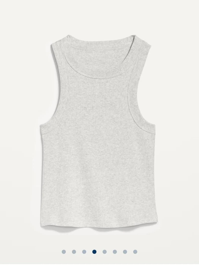 May include: A light grey ribbed vest top with a scoop neckline and wide shoulder straps. The sleeveless top is made of a soft, textured fabric and has a rounded hemline. The casual top is suitable for layering or wearing on its own.