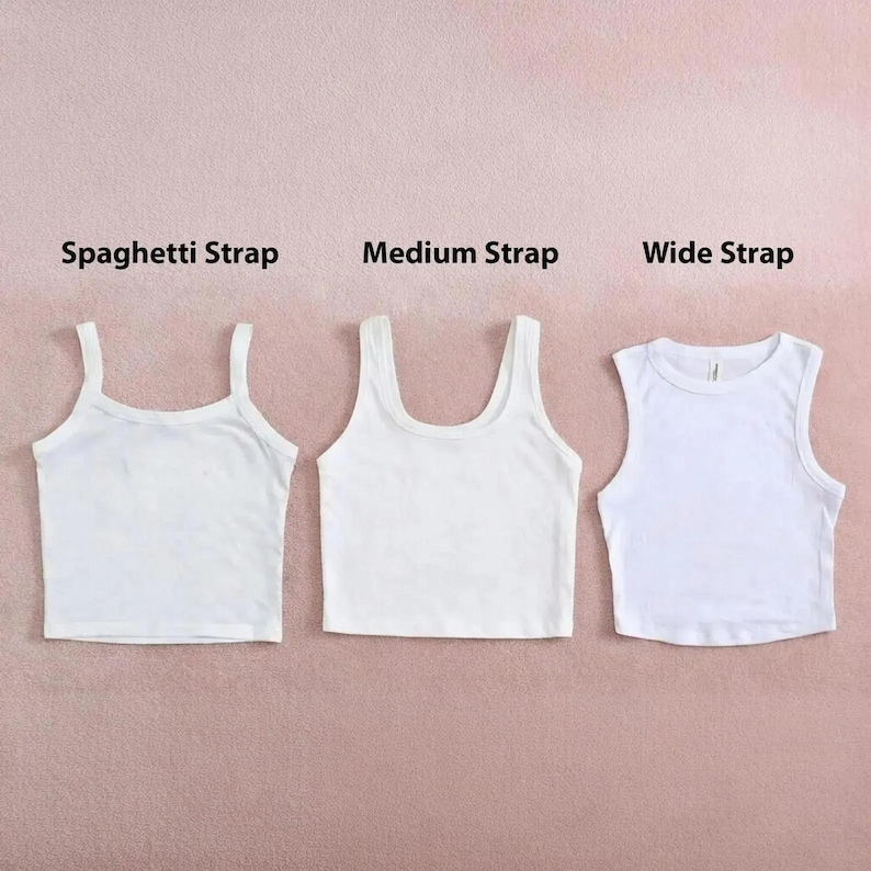 May include: Three white crop tops with varying strap designs: spaghetti strap, medium strap, and wide strap. The tops are arranged on a pink backdrop, with text labels indicating each style.