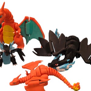 Könnte beinhalten: Drei bewegliche Plastik-Drachenfiguren. Eine ist rot mit grünen Flügeln, eine ist schwarz mit blauen Flammen und eine ist orange mit gelben Flammen.