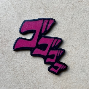May include: A pink and black stylised "ORA ORA" graphic. The graphic is a popular meme from the anime series JoJo's Bizarre Adventure.