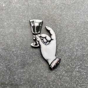May include: A black and white illustration of a hand holding a stemmed glass.
