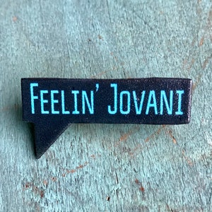May include: Black and white speech bubble pin with the text "Feelin' Jovani" in blue.