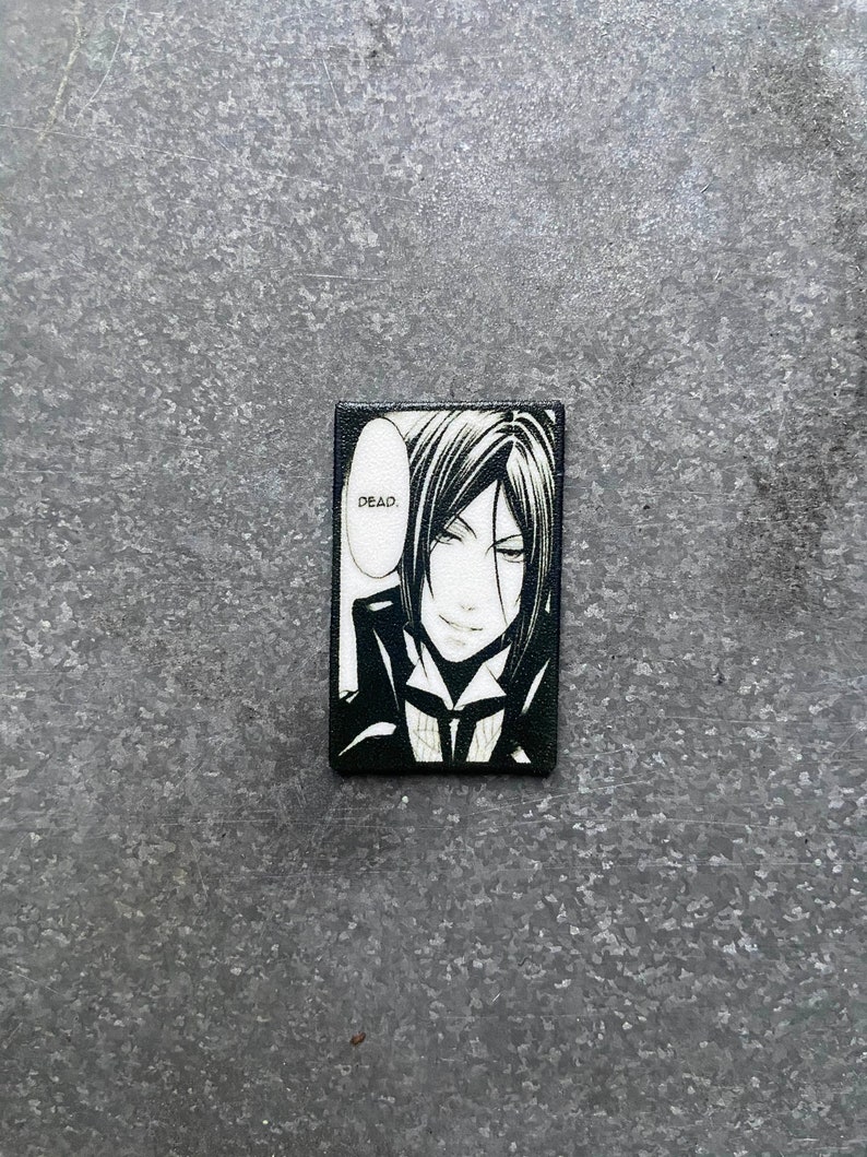 May include: Black and white illustration of a character from the anime series Black Butler. The character has black hair and is wearing a black suit. The character is saying "Dead."