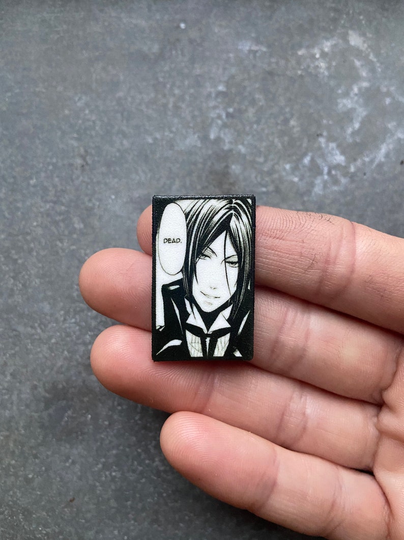 May include: Black and white anime character with black hair and a white collar, with the word "DEAD." in a speech bubble above their head.