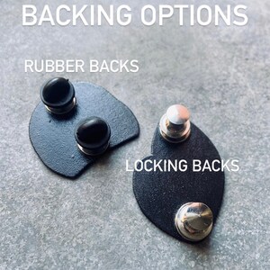 May include: Two types of pin backs: rubber backs and locking backs. The rubber backs are black and the locking backs are silver.