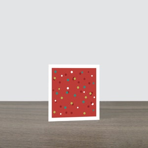 May include: A red card with a white border and a pattern of white, red, yellow, and teal dots.