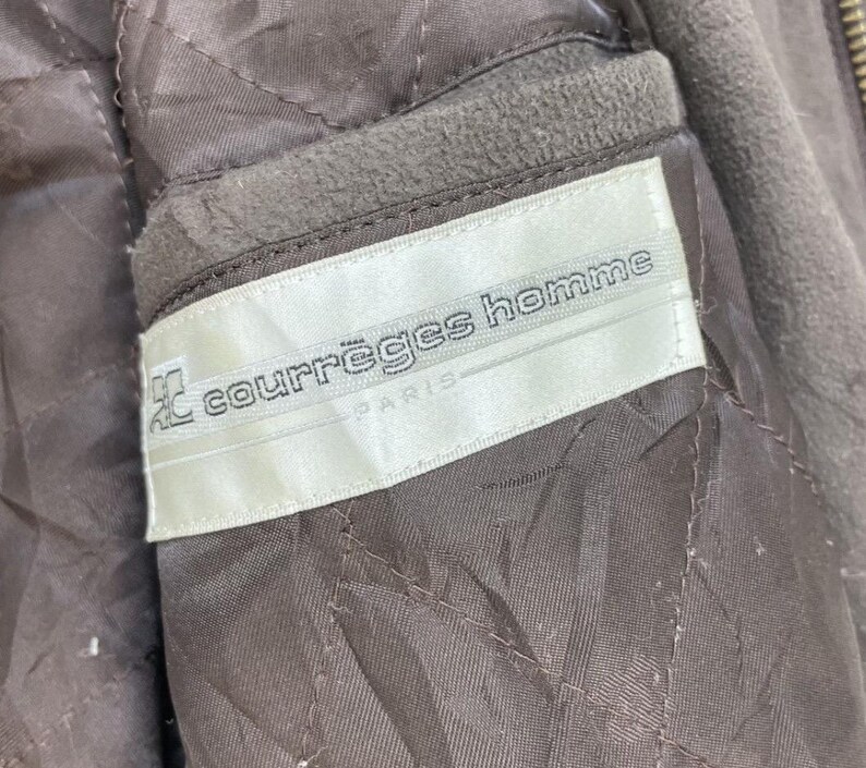 May include: A white label with the text "courr&egrave;ges homme PARIS" in black lettering.