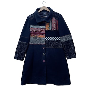 May include: A black long-sleeved coat with a patchwork design on the front. The patchwork is made up of different fabrics with various colors and patterns, including red, orange, yellow, blue, and white. The coat has a button closure and a collar.