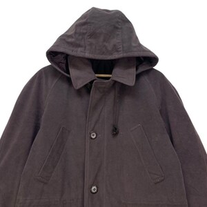 May include: A dark gray hooded jacket with a zipper closure and two pockets. The jacket has a drawstring hood and a relaxed fit.