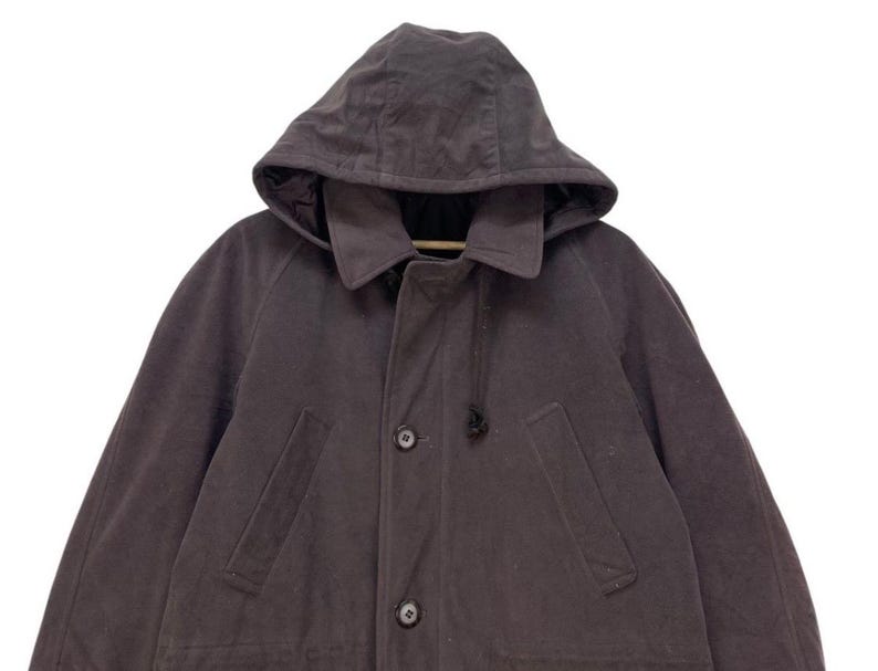 May include: A dark gray hooded jacket with a zipper closure and two pockets. The jacket has a drawstring hood and a relaxed fit.