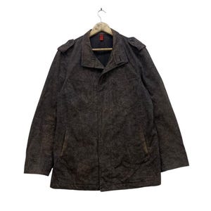 May include: A brown corduroy jacket with a button-up front, two chest pockets, and shoulder epaulets. The jacket is hanging on a wooden hanger against a white background. The jacket's length is approximately 30 inches.