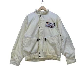 May include: A white jacket with a zipper closure and a patch on the left chest that reads "Grand Prix Formula One Championship 85".