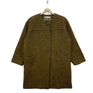 May include: An olive green vintage coat with a textured finish. The coat has a round collar, three buttons, and two front pockets. The sleeves are three-quarter length. It is suspended from a wooden hanger.