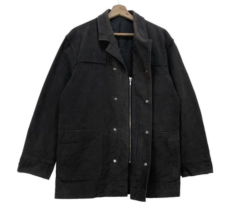 May include: A black zip-up jacket with a long sleeve, two pockets, and a button closure. The jacket has a textured fabric and a relaxed fit.