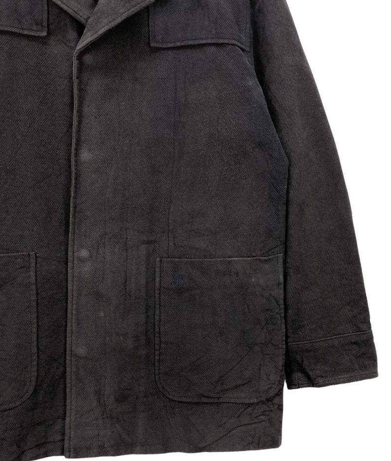 May include: A dark gray corduroy jacket with a button-up front, two flap pockets, and a single pocket on the left chest. The jacket has a collar and long sleeves.