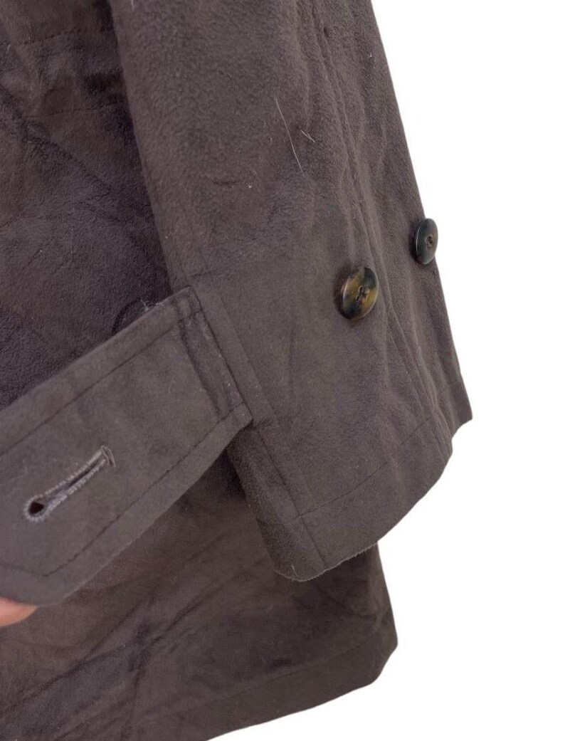 May include: A brown jacket with a buttoned cuff and two buttons on the front. The jacket is made of a soft, textured fabric.