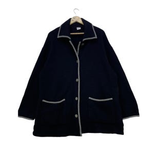 Puede incluir: Una chaqueta de forro polar azul marino con ribete gris alrededor del cuello, los bolsillos y la tapeta de botones. La chaqueta tiene dos bolsillos delanteros y cierre de botones.