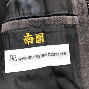 May include: A black corduroy jacket with a zipper closure. The jacket has a white label with the text "courr&egrave;ges homme" and a yellow label with the text "和" in Japanese.