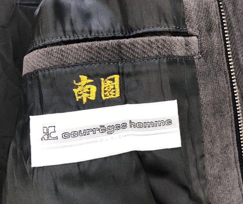 May include: A black corduroy jacket with a zipper closure. The jacket has a white label with the text "courr&egrave;ges homme" and a yellow label with the text "和" in Japanese.