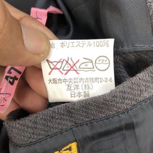 May include: A white care label with black text and symbols. The text reads "地 ポリエステル100%" "ドライ" "中" "大阪市中央区内淡路町2-2-6" "互洋(株)" "日本製".