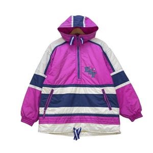 Peut inclure: Veste anorak à capuche rose, blanche et bleu marine. Elle est dotée d'une fermeture à demi-zip, d'un cordon de serrage à l'ourlet et d'un petit logo brodé. Le design comprend des rayures horizontales et des panneaux colorés.
